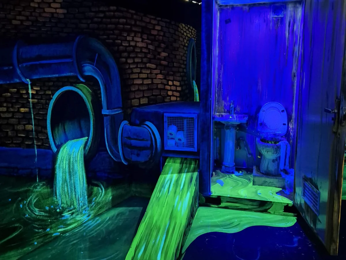 Nagebouwd riool met een groen oplichtende slijmstroom op de blacklight-minigolfbaan in Zaanstad
